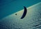 A lone paraglider over a silver sea with dark clouds at dusk