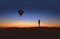 A lone person observes an hot air balloon at sunrise