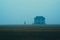 a lone person standing in front of a house in the fog