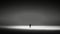 a lone person standing in the middle of a dark beach.