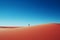 a lone person standing in the middle of a red sand dune