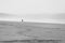 Lone person walking on the beach in the distance through the mist