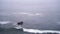 A lone rock is splashed by pacific ocean waves on a cold desolate morning