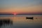 Lone rowboat in calm water at sunset