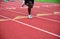 Lone runner legs and feet race down a red numbered athletic track