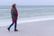 Lone sad beautiful girl walking along the shore of the frozen sea on a cold day, rubella, chicken with a red scarf on the neck