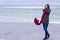 Lone sad beautiful girl walking along the shore of the frozen sea on a cold day, rubella, chicken with a red scarf on the neck