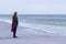 Lone sad beautiful girl walking along the shore of the frozen sea on a cold day, rubella, chicken with a red scarf on the neck