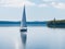 A lone sailboat gliding across the calm waters of a lake.