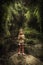 Lone scared child in isolation lost among lush green trees foliage and plants in cave in tropical forest