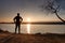 Lone sportsman looking at colorful sunset on shore of autumn lake