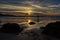 Lone surfer walks into the sea under a dramatic sunset sky