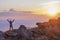 Lone tourist enjoying an amazing sunset with raised arms