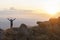 Lone tourist girl enjoying an amazing sunset in the mountains with raised arms. Vacation and social distancing in the mountains