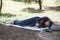 A lone tourist hid in a sleeping bag and sleeps on the ground in a city park, a homeless person sleeps in the afternoon in the