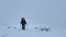A lone traveler walks along the snowy hills.