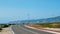 Lone unidentifiable walker or runner on sidewalk at Praia do Guincho heading towards Cabo da Roca near Sintra, Portugal