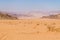 A lone vehicle in the vast sandy and rocky landscape in Wadi Rum, Jordan in summertime