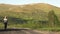 Lone Wanderer in shirt and trousers goes on a hilly road in the mountains