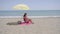 Lone woman sitting on beach under umbrella