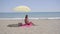Lone woman sitting on beach under umbrella