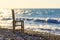 Lone wooden chair on the seashore at sunset and waves