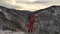 A lone young male hiker stands on top of a mountain at sunset.