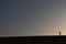 A lonely of adventurer salutes from the top of a grand sand dune while enjoying a beautiful summer sunset in Dakhla Oasis, Egypt