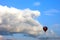 Lonely air baloon flying in front of white puffy clouds against