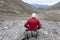 Lonely backpacker sitting on stone and looking at distance, the only one way through the valley