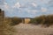 Lonely beach chair is standing at the beach at the end of a sandy footpath between dunes