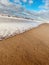 Lonely beach with focus on pristine sand and the waves