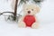 A lonely bear with a big red heart is sitting on the snow waiting. with love on holidays