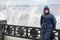 Lonely beatyfull girl in icy splashes of storm waves on the riverside with metal embankment