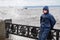 Lonely beatyfull girl in icy splashes of storm waves on the riverside with metal embankment