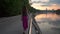 Lonely beautiful brunette girl walking on park embankment at sunset. Slow motion shot