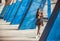 Lonely beautiful girl standing between blue columns of grunge city area. Young woman drinking coffee in urban space