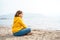 Lonely beautiful sad girl teenager sits thoughtfully on sand sea beach. Dreams,anxiety,worries about future,school