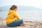 Lonely beautiful sad girl teenager sits thoughtfully on sand sea beach. Dreams,anxiety,worries about future,school