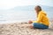 Lonely beautiful sad girl teenager sits thoughtfully on sand sea beach. Dreams,anxiety,worries about future,school