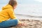 Lonely beautiful sad girl teenager sits thoughtfully on sand sea beach. Dreams,anxiety,worries about future,school