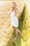 Lonely beautiful young blonde girl in white dress with straw hat