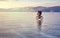 Lonely biker with backpacks on bike on ice of Lake Baikal. Against the background of sunset sky, ice surface. Winter sport concept