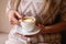 lonely blonde girl sitting on a windowsill with a white cup with coffee with a heart, romantic mood.