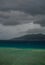 Lonely boat in the storm. Coast line and black clouds in the background