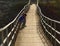 Lonely boy sitting on a suspension bridge