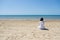 Lonely brunette woman with lobg hair on a beach and looking on sea. Back view.