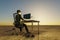 lonely businessman at pc work place in large desert environment remote work and digital nomad and climate crisis concept 3D