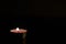 A lonely candle burns in the darkness