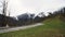 Lonely car on a mountain road turn on snowy peaks and cloudy heavy sky background. Stock footage. Mountain road car trip